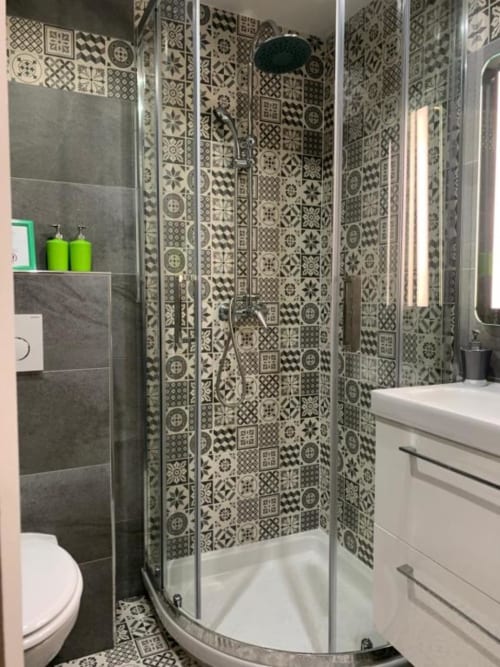 Modern bathroom in Azur Studios Cannes with patterned tile shower enclosure, white vanity, and toilet