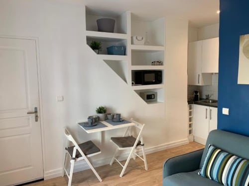 Superior Studio apartment at Azur Studios Cannes with dining table, kitchenette, built-in shelving, and blue accent wall