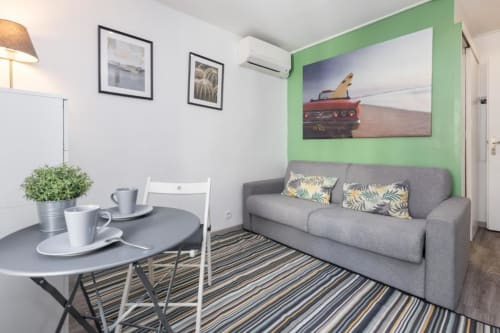 Superior Studio at Azur Studios Cannes with gray sofa, green accent wall, dining table, and kitchenette area
