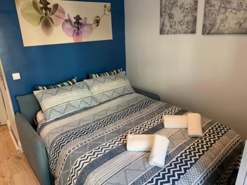 Bedroom at Azur Studios Cannes with blue accent wall, patterned bedding, and white towels on bed