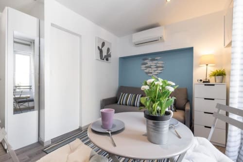 Superior Studio at Azur Studios Cannes with dining table, potted flowers, sofa, blue accent wall, and modern amenities.