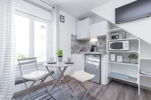 Modern kitchenette with dining area in Superior Studio at Azur Studios Cannes, featuring white cabinetry, appliances, and