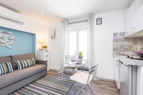Superior Studio at Azur Studios Cannes featuring gray sofa, kitchenette, dining area, and blue accent wall with modern décor