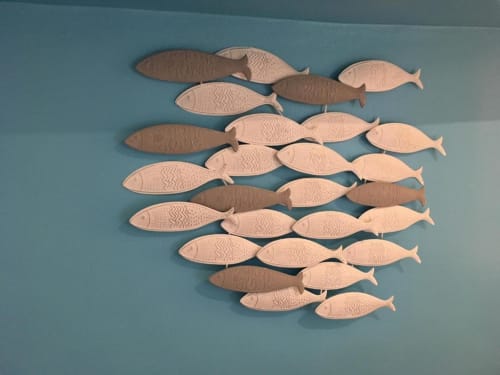 Decorative wooden fish wall art in Cannes hotel room featuring carved fish in various shades arranged on turquoise wall
