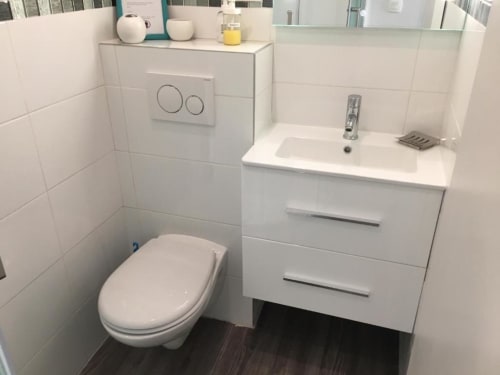 Modern white bathroom in Superior Studio at Azur Studios Cannes with toilet, sink vanity, and dark wood flooring