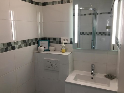 Modern bathroom in Superior Studio at Azur Studios Cannes with white tiles, sink, toilet, and glass shower enclosure