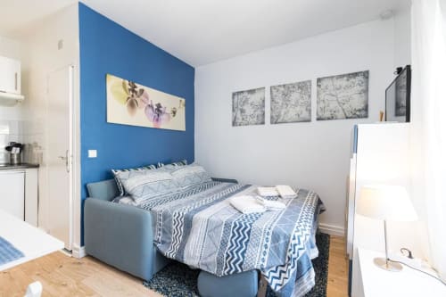 Modern studio bedroom at Azur Studios Cannes with blue accent wall, queen bed, and kitchenette