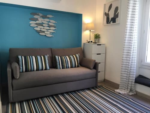 Modern studio living room at Azur Studios Cannes with gray sofa, turquoise accent wall, and striped rug