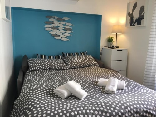 Modern bedroom at Azur Studios Cannes with turquoise accent wall, polka dot bedding, and nautical fish wall art
