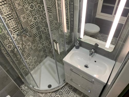 Modern bathroom with patterned tile shower, white sink, and illuminated mirror at Azur Studios Cannes