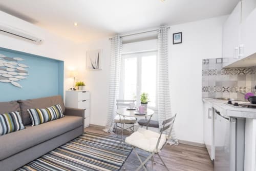 Modern studio apartment at Azur Studios Cannes with gray sofa, kitchenette, and bright living space