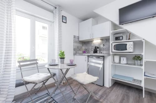 Modern studio kitchenette with dining area at Azur Studios Cannes, featuring white cabinetry and compact furnishings
