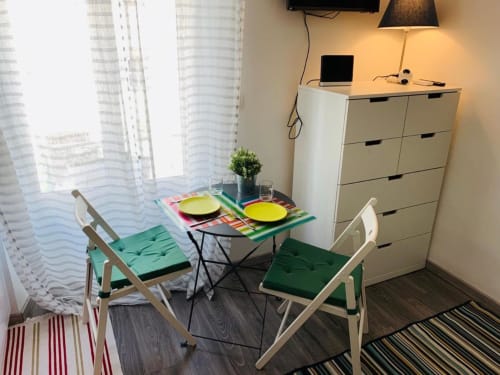 Azur Studios Cannes dining area with two white chairs, colorful table setting, and city views