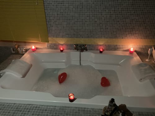 Baignoire luxueuse avec pétales de cœur rouges et bougies allumées à la suite Diane de Poitiers du Château de Ré au Petit Pressigny