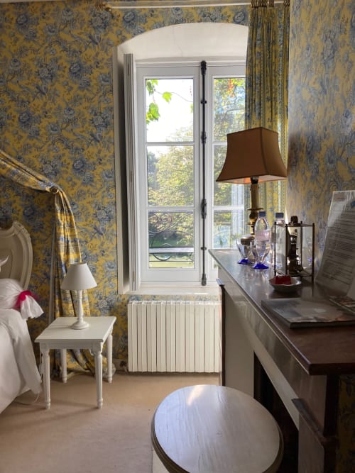 Chambre Dauphine du Château de Ré avec papier peint toile jaune, vue sur le jardin, mobilier élégant et décor d'époque