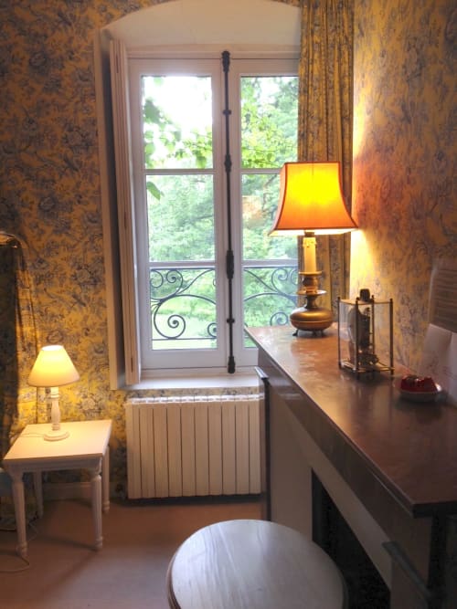 Chambre Dauphine au Château de Ré avec papier peint raffiné, portes donnant sur le jardin et lampes ambrées