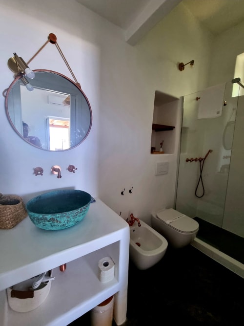 Modernes Badezimmer in der Miravilla Salina B&B mit türkisem Aufsatzwaschbecken, rundem Spiegel und Regendusche in Santa Marina Salina