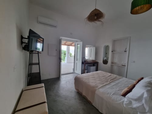 Helles modernes Schlafzimmer in Miravilla Salina mit Doppelbetten, TV, Balkon mit Meerblick und minimalistischer Einrichtung in Salina, Sizilien
