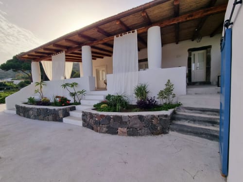 Strandveranda von Miravilla Salina mit weißen Säulen, hölzerner Pergola, Steinkübeln und Meerblick in Santa Marina Salina
