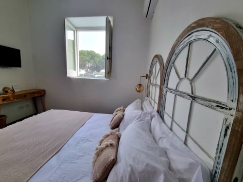 Küstenzone-Schlafzimmer in Miravilla Salina mit Meerblick-Fenster, vintage Metallbett in Weiß und rustikale Holzmöbel