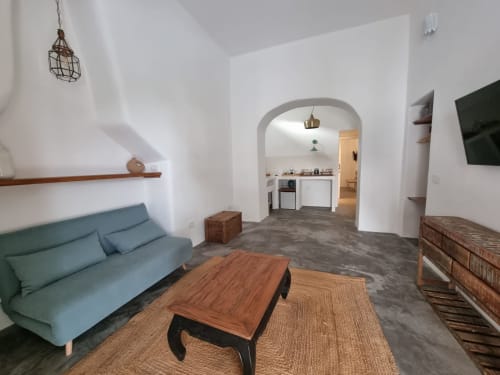Modernes Wohnzimmer in Miravilla Salina mit blauem Sofa, Holztisch und Küche sichtbar durch Bogentür in Salina