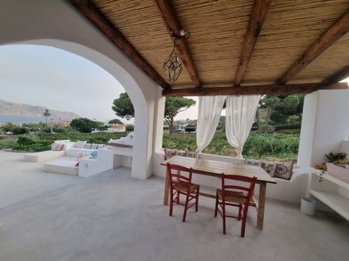 Überdachte Terrasse von Miravilla Salina mit roten Stühlen, weißen Liegen und Meerblick über Santa Marina Salina