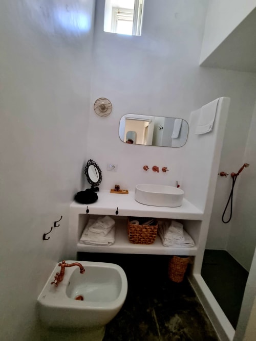 Modernes Badezimmer in Miravilla Salina mit weißem Waschtisch, rundem Waschbecken, Spiegeln und geflochtenen Aufbewahrungskörben
