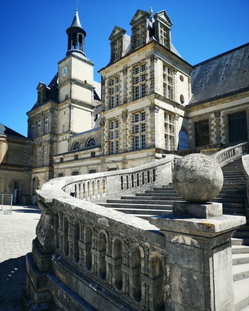 Cour historique du château de Chartrettes avec escalier en pierre et sphère sculptée