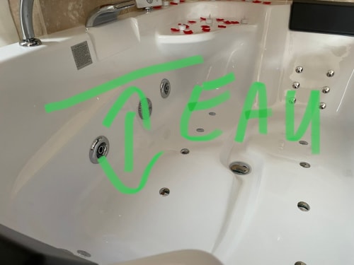 Baignoire balnéo luxueuse avec texte vert et pétales de rose rouge au spa jacuzzi Suite d'amour à Chartrettes