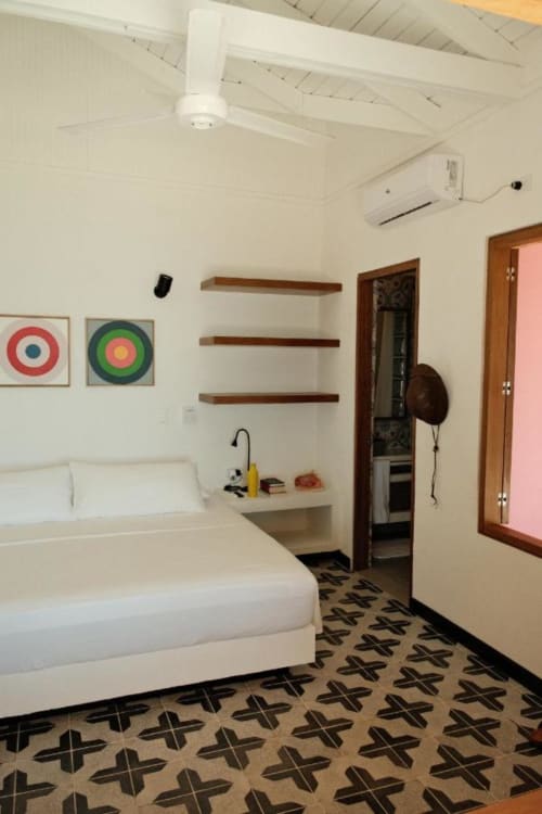 Habitación moderna en el boutique lodge Seaflower con cama blanca, estantes de madera, arte mural colorido y piso de diseño en San