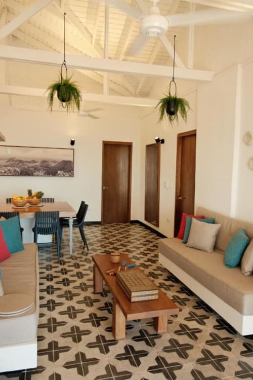Habitación de huésped en el boutique lodge Seaflower con sofá beige, comedor, plantas colgantes y piso de cerámica geométrica en San Andrés