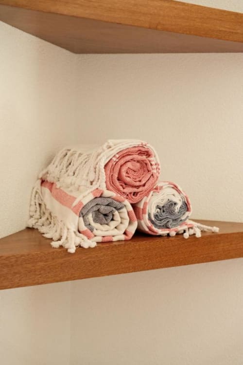 Toallas enrolladas en tonos coral y crema exhibidas en estante de madera en la boutique lodge Seaflower, San Andrés