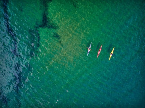 Vista aérea de tres kayaks coloridos navegando en aguas turquesas cerca del lodge boutique Seaflower, San Andrés y Providencia.