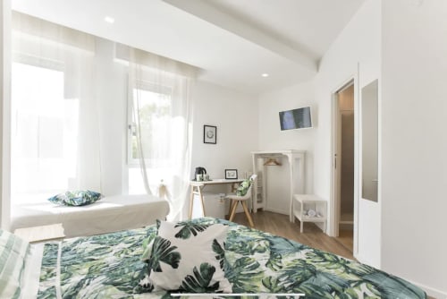 Bright modern bedroom at Catalogna10 in Alghero with tropical bedding, desk, window seat and city views