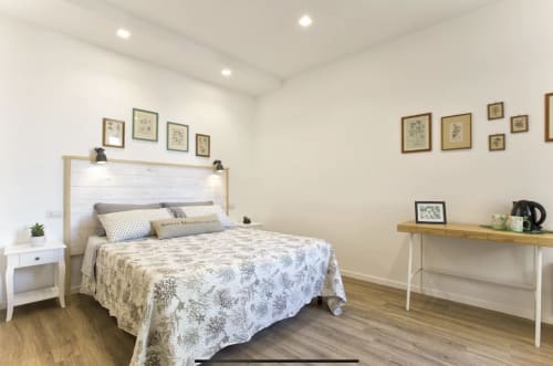 Modern double bedroom at Catalogna10 Rooms in Alghero with city view, featuring white headboard and botanical wall art