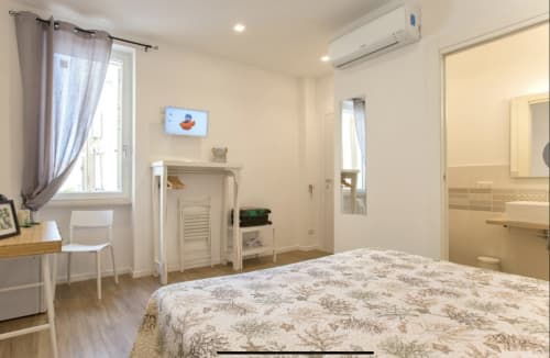 Bright double room at Catalogna10 in Alghero with queen bed, modern amenities, AC unit, and city views through windows