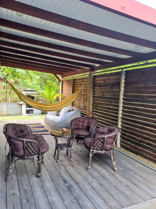 Terrasse couverte en bois avec sièges confortables, hamac et vue sur un jardin tropical luxuriant à Villa Tourmaline, Martinique