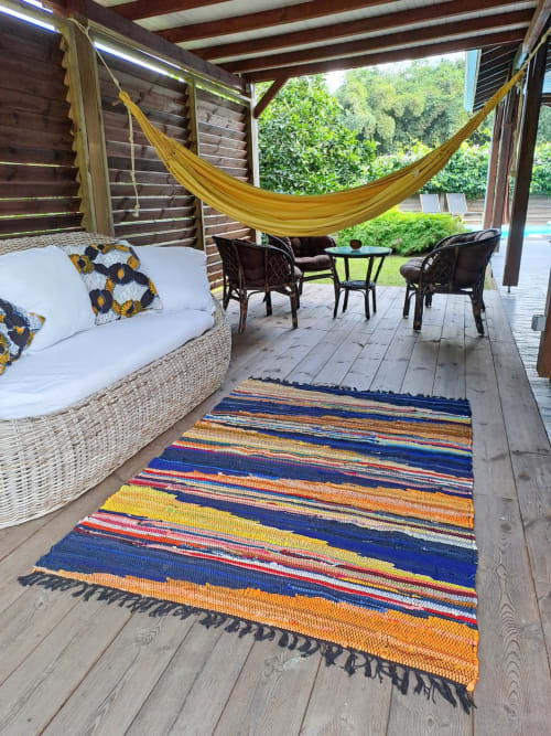 Patio couvert de la Villa Tourmaline au Lorrain : canapé blanc en rotin, hamac jaune, tapis rayé coloré et noir