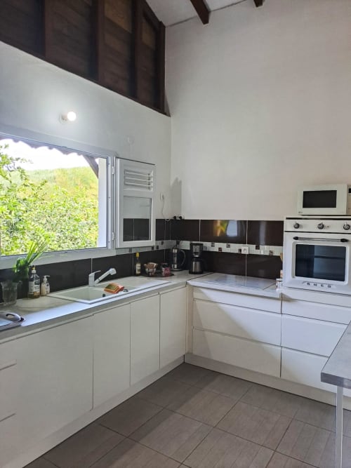 Cuisine moderne avec armoires blanches, dosseret noir et appareils en acier inoxydable à la Villa Tourmaline au Lorrain