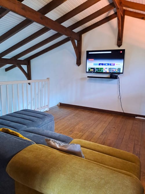 Espace de vie loft moderne à Villa Tourmaline avec sièges bleu et jaune, TV écran plat, poutres apparentes et puits de lumière au