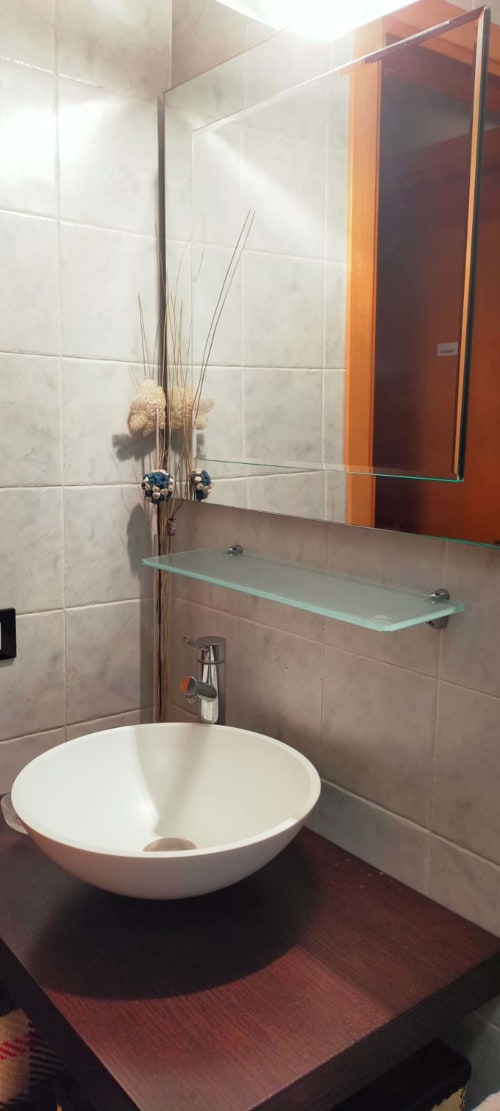Modern bathroom sink with round white basin, mirror, and decorative dried flowers at Casa Meravigliosa apartment in