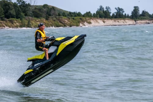 Hombre en moto acuática amarilla y negra navegando a toda velocidad en el océano cerca de Playa Bungalow Buda, Chipiona