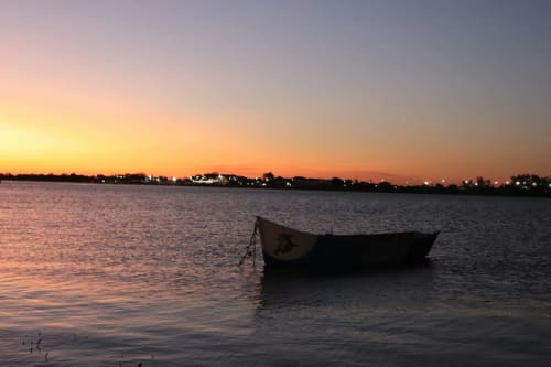 Silueta de barca al atardecer sobre aguas tranquilas cerca de Bungalow Buda Beach, Chipiona