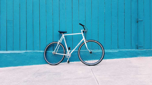 Bicicleta blanca contra pared turquesa en Bungalow Buda Beach, Chipiona