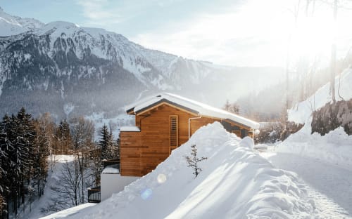 Chalet en bois moderne niché dans le paysage enneigé des Alpes à Les Houches, Chamonix Mont-Blanc avec ses pics couverts de neige