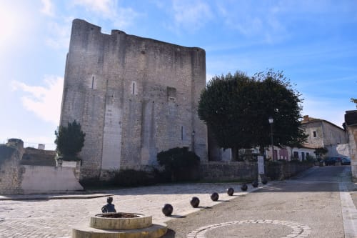 Tour en pierre médiévale à la place Verrières de l'hôtel Les Deux Porches, avec architecture historique et bâtiments anciens