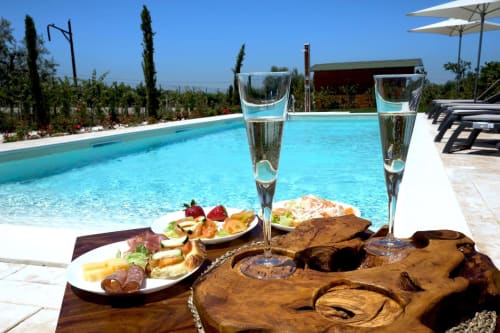 Champagne flutes and gourmet platter by pool at Casale 905 luxury B&B in Crecchio, Italy