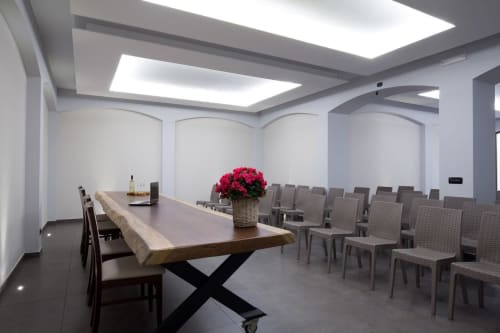 Modern meeting room at Casale 905 B&B in Crecchio with wooden table, pink flowers, and rows of gray chairs