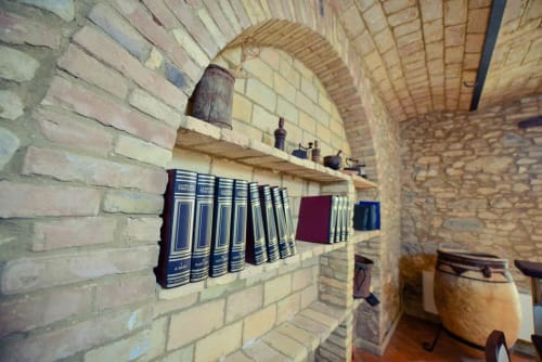 Rustic brick archway at Casale 905 B&B in Crecchio with wooden shelves displaying antique books and vintage decor