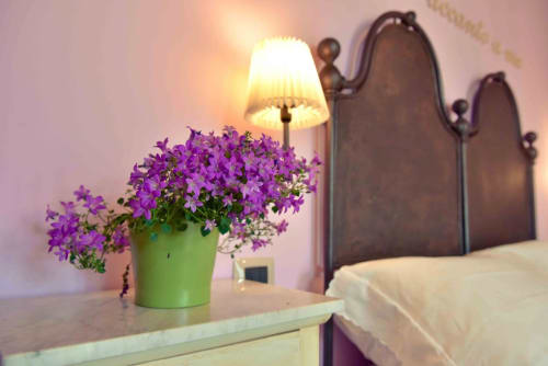 Purple petunias in green pot beside lamp at Casale 905 B&B bedroom, Crecchio Italy